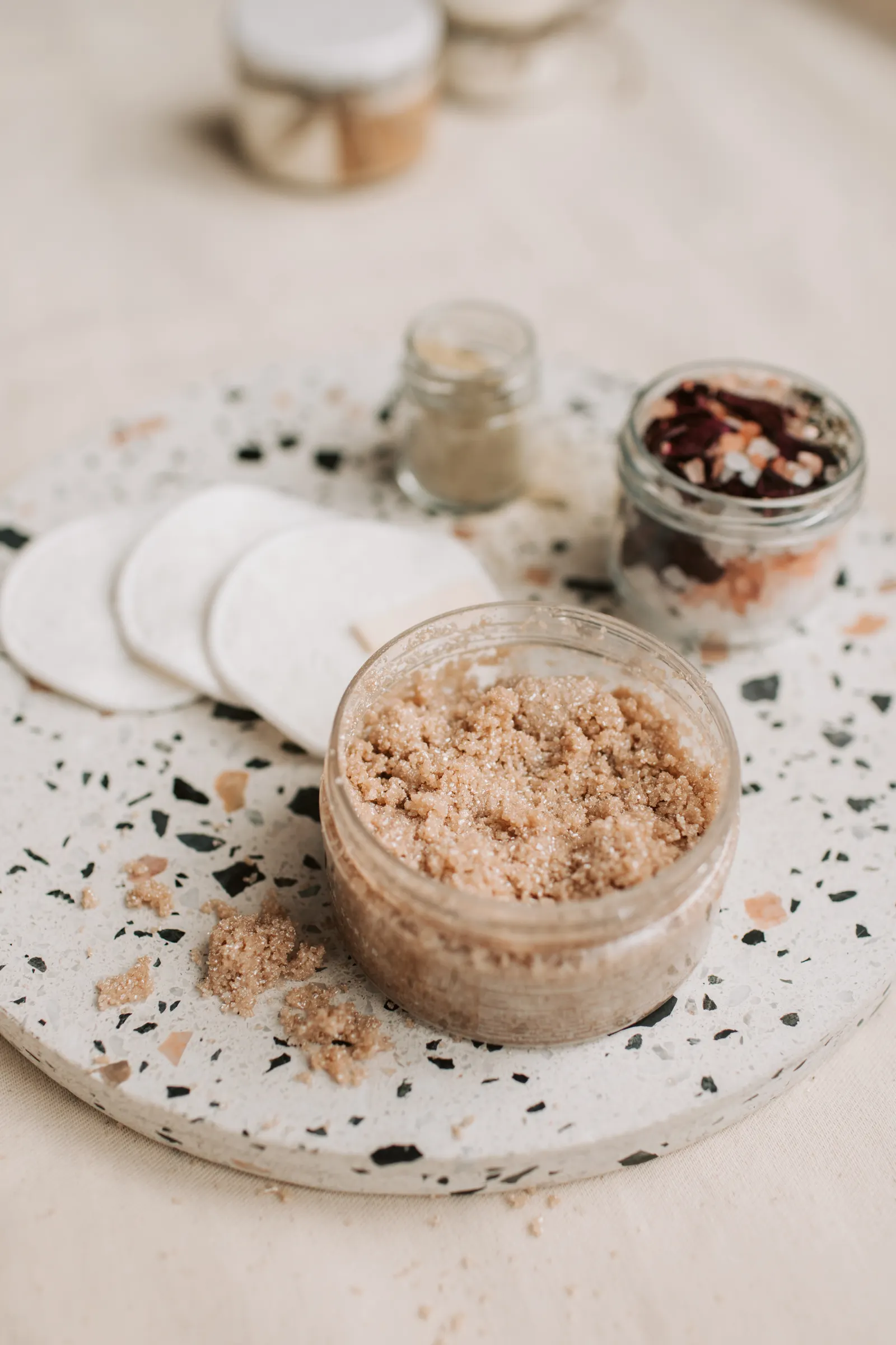 Natural body scrub and cotton pads in an eco-friendly flat lay
